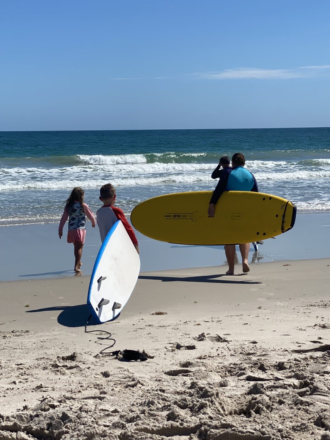 A Family carries their surfboards on the beach for a day on the waves.