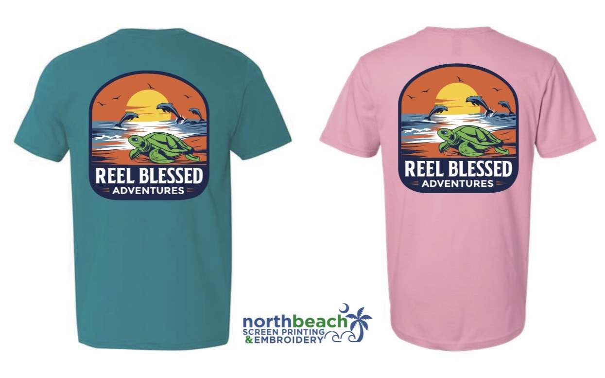 A t shirt back featuring a prominent turtle on a beach with dolphins in the back ground and birds flying with the sunset.